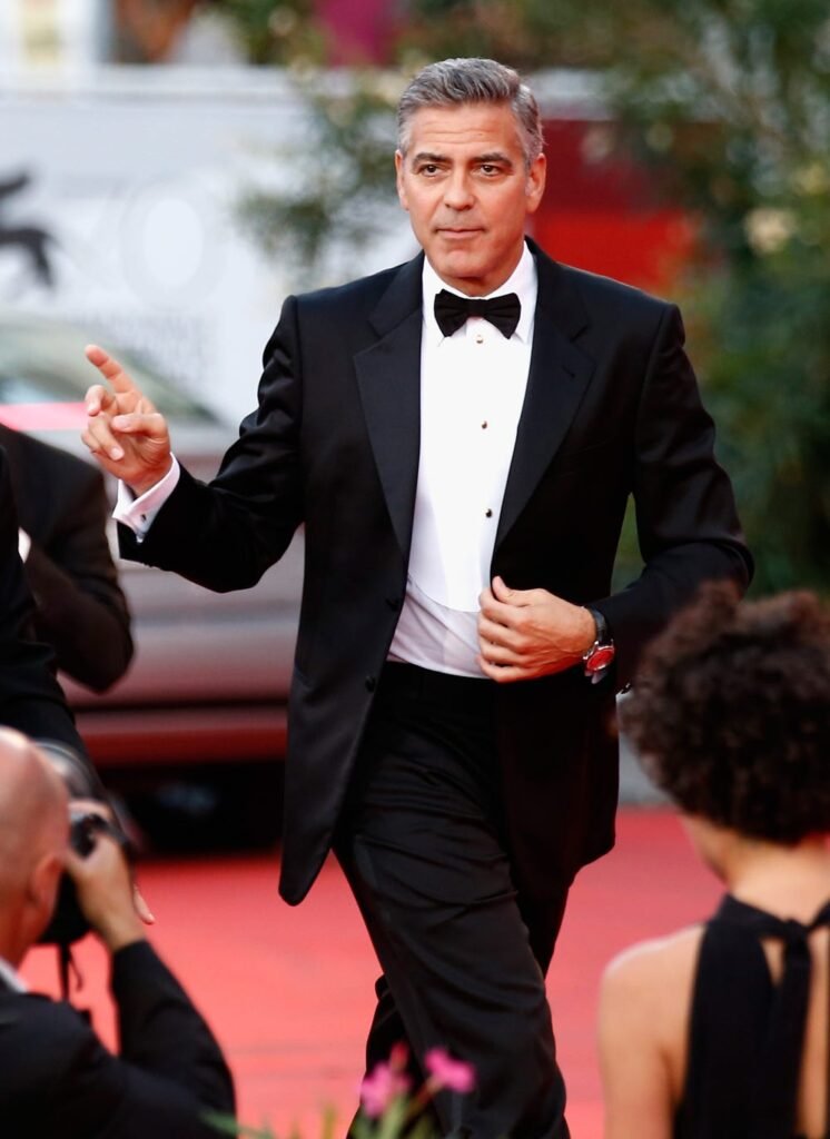 George Clooney com um terno caminhando em tapete vermelho